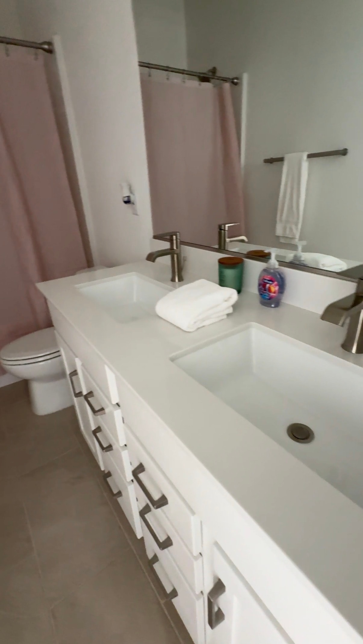 Airbnb bathroom with dual sinks and pink curtain