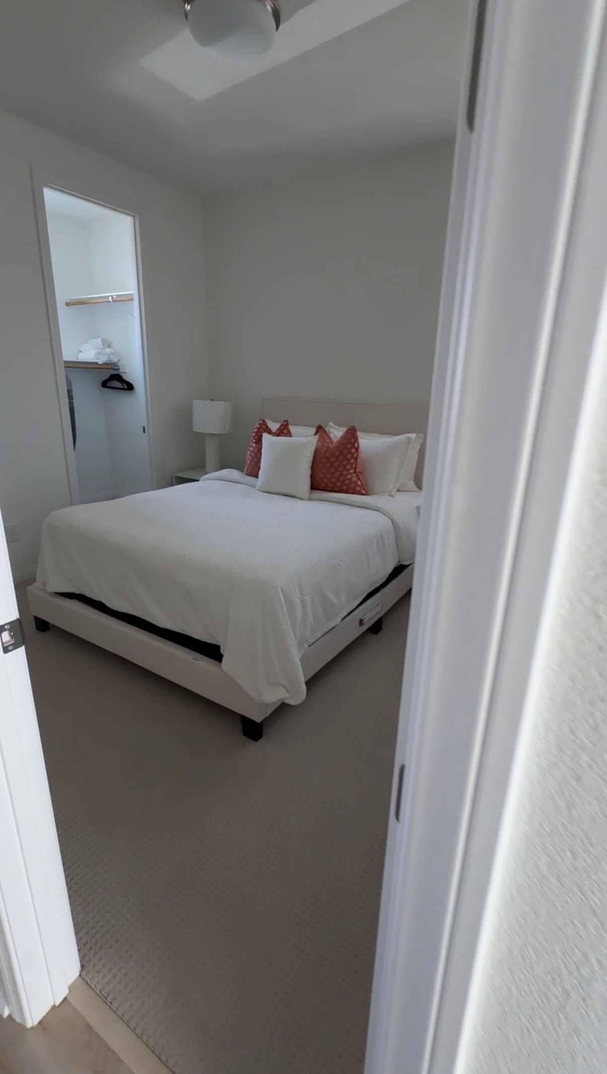 Airbnb bedroom with white linens and red pillows